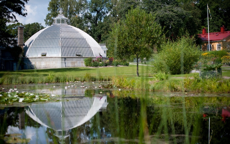 Ett kupolformat växthus, med en damm framför.